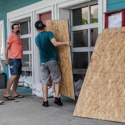 A group of workers board restaurant windows in preparation for a hurricane.