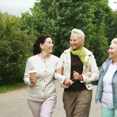 Three elderly women walking in the park.