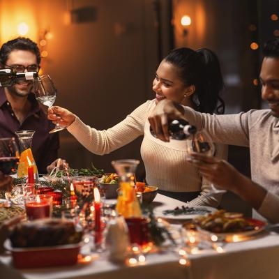 A group of happy friends pouring wine in their glasses during Christmas dinner.
