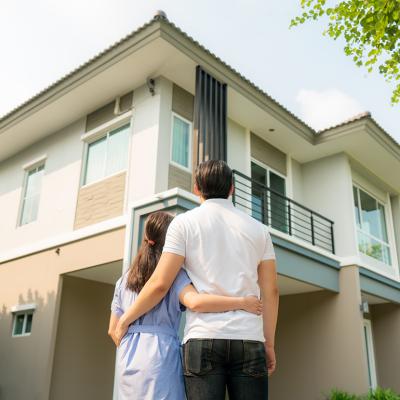 Back portrait of a young couple standing in front of their newly-bought home.