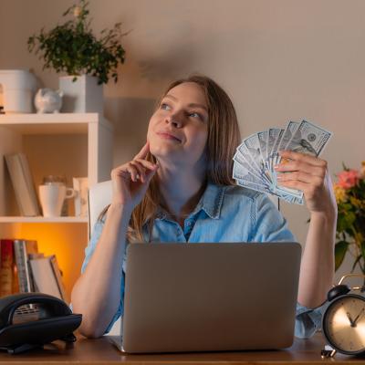 A female manager holding cash daydreaming in an office.