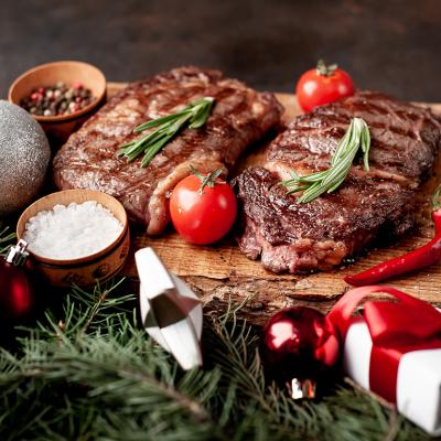 Beautifully grilled ribeye steaks prepared on a wooden board for Christmas.