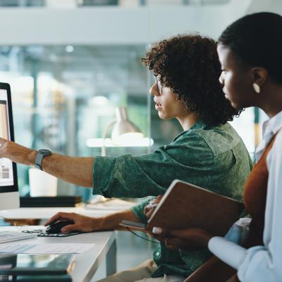 Two coworkers collaborating on a task in their office.