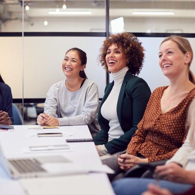 A group of business women listening to a presentation in a meeting room.