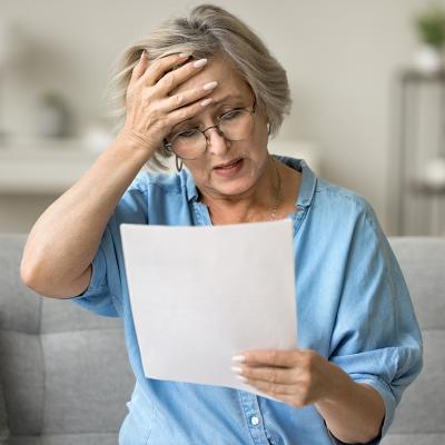 A frustrated senior woman reading a document at home.