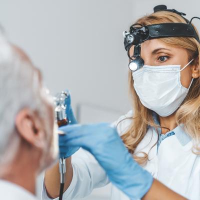 Close up of a female otolaryngologist making an examination of a senior patient's oral cavity.