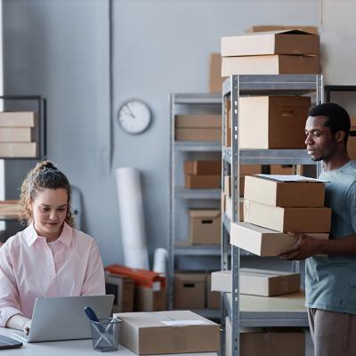 Two members of a small business in a warehouse preparing to send packages.