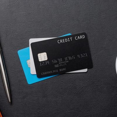 A flat lay of a stack of credit cards with a pen and cup of coffee on each side.