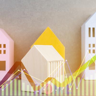 Colorful wooden figures of homes illustrated with finance chart graphics.