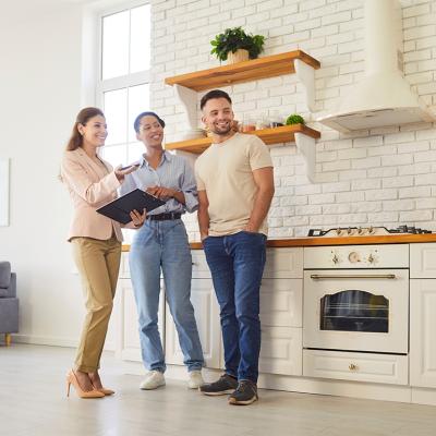 A female broker giving a young couple a tour of a house.
