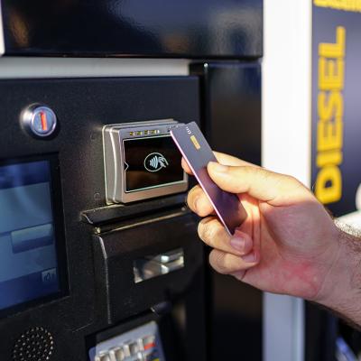 Hand of a person paying using card by the fuel pump at a gas station.