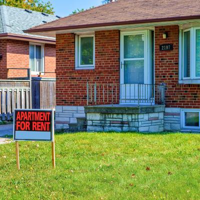 An 'apartment for rent' sign on a house lawn.