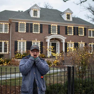 Person poses with the classic "Home Alone" pose with hands pressed to cheeks outside the gate of the home used in the film "Home Alone," in Winnetka, IL