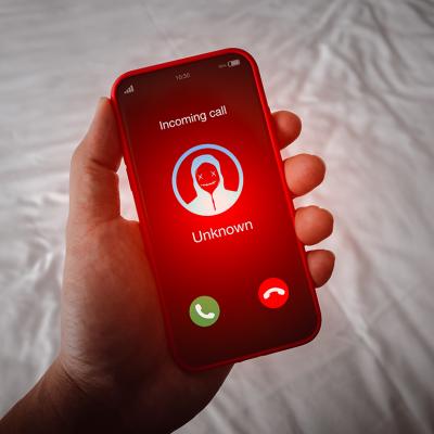 A person's smartphone receiving an unknown call with a red alert.
