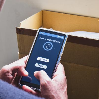A man looking at a shopping app on his phone displaying options to replace or return a product.