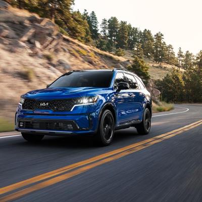 A front 3/4 view of a blue 2023 Sorento SX driving on a mountain road.