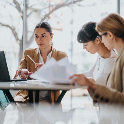 A group of three female professionals in a coworking space.