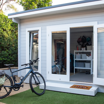 A nice shed with the doors open and a bike parked in front of it. 