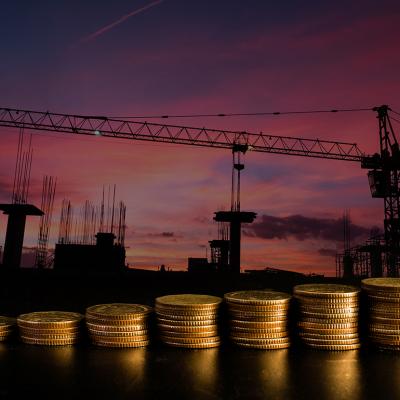 A row of stacked coins with an estate construction site background.