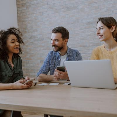 A 3-member creative team engaged together in a discussion in an office.