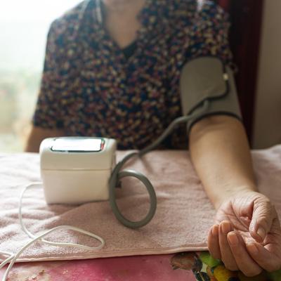 A senior woman getting her blood pressure checked using a digital monitor.