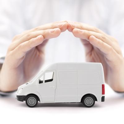 A figure of a small transport van protected by hands of a car insurance agent.
