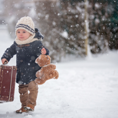 Baby playing with teddy bear in the snow.