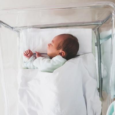 A newborn baby sleeping in a hospital crib.