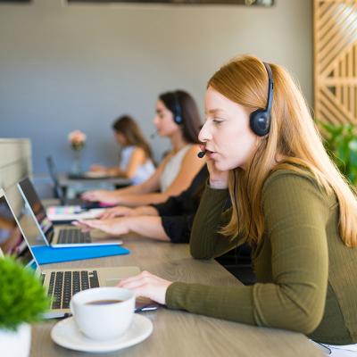 A row of female customer service representatives taking calls in their office.