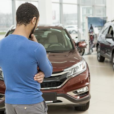 Rear view of a man choosing a car at a dealership.