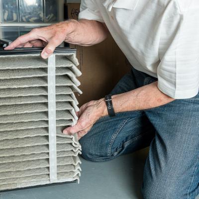 Man changing a folded dirty air filter of an HVAC system.