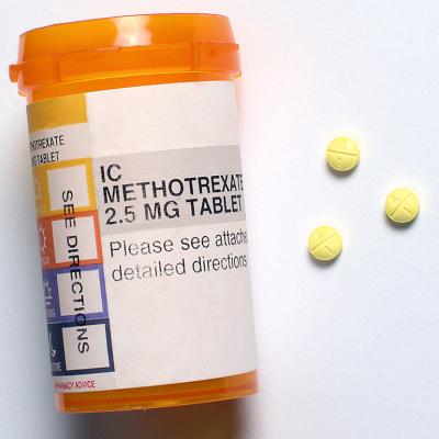 Three generic Methotrexate pills beside a prescription bottle.