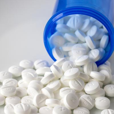 Metformin pills spilling out of a blue prescription bottle.