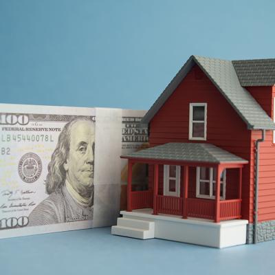 US dollar banknotes and a figure of a home.