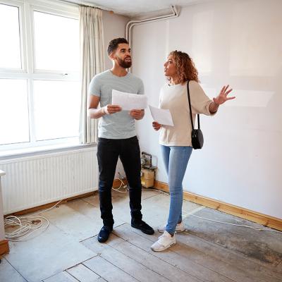 A couple surveys a house's area for renovation.