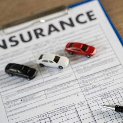 Three small figures of cars on top of a car insurance document.