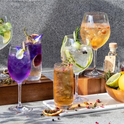 A display of assorted homemade herbal cocktails in wine glasses.