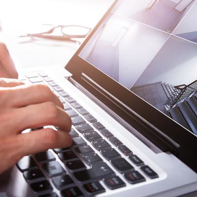 Person monitors a split screen view of CCTV footage using a laptop.