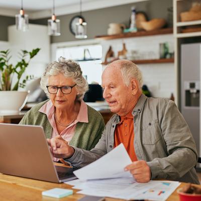 A senior couple using a laptop to review documents.
