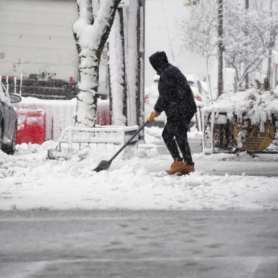 A person shovels snow in a neighborhood.