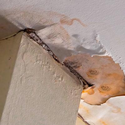 A corner of a home's ceiling falling apart from mold and water damage.