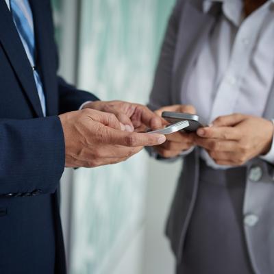 Two businesspeople on their phones exchanging numbers.