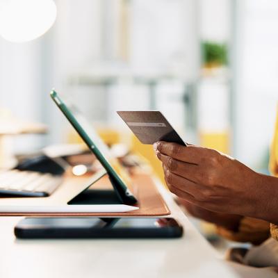 A businesswoman holding up a credit card while at work in the office.