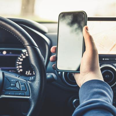 Person's hand holding up a smartphone while driving.