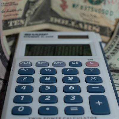 A calculator with a background of US dollar banknotes.