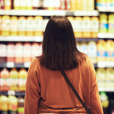 A person looking at shelves of juice at a grocery store.