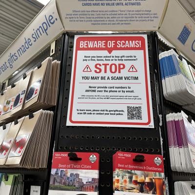 A large 'beware of scams' sign on display at a gift card aisle in a store.