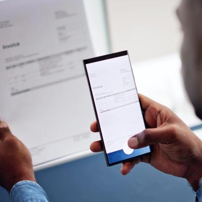 A man taking a photo of an invoice document using a phone.
