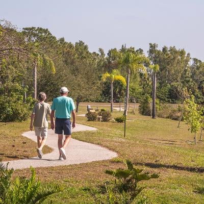 Two seniors walking a trail at a park during spring time.