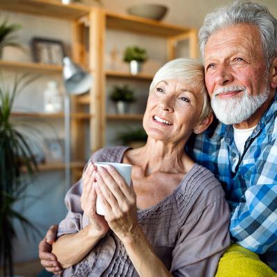 A senior couple hugging and looking out while having a coffee in the morning.